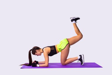 Spor üniformalı çekici bir kız bacak kaslarını germek için yukarı doğru hamle yapıyor..