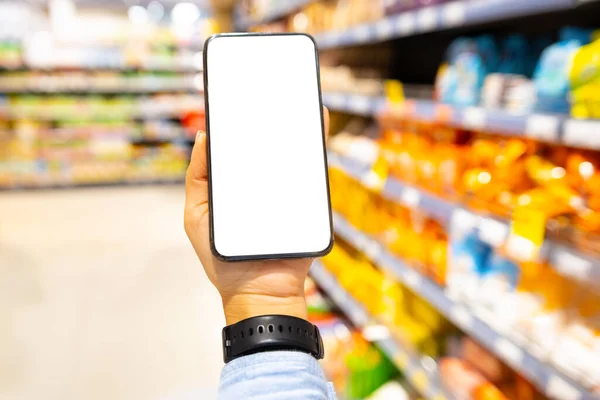 Close up foto de um homem mão vestindo relógio digital segurando telefone inteligente com tela na loja entre as prateleiras. — Fotografia de Stock