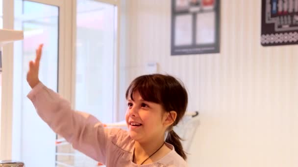Vídeo de una joven sonriente extendiendo la mano para medir la temperatura del aparato dentro de la tienda en tiempo pandémico. — Vídeo de stock