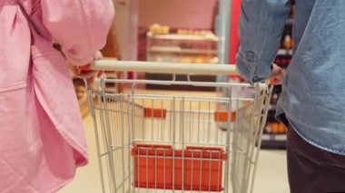 Alışverişe giderken kadın ve erkeğin el arabası, pembe kot gömlek giyen kadın ve mavi kot gömlek giyen adam..