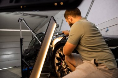 İşçi, siyah araba gövdesini restore ediyor. Yüksek kalite fotoğraf