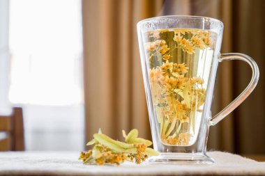 Şeffaf bir fincanda, ahşap bir masada ıhlamur çayı..