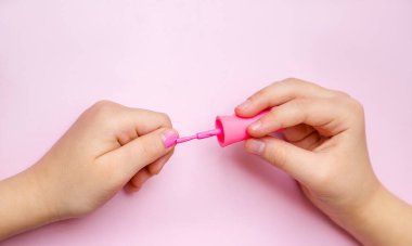 Kız tırnaklarını pembe ojeyle boyuyor..