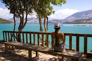 Bir genç bankta oturur ve deniz manzarasına bakar..