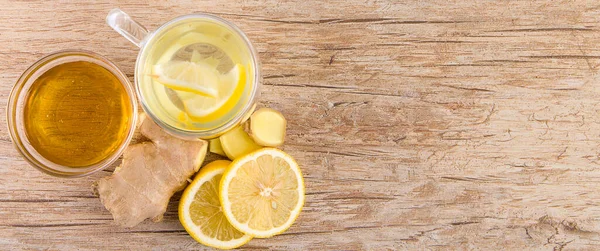 Lemon and ginger tea, honey and slices of lemon and ginger on a wooden background.