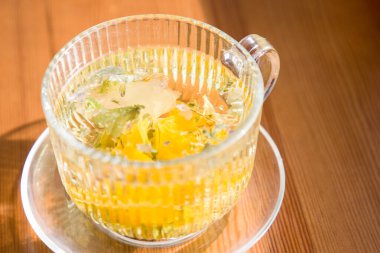 Bitki çayı ve nane şekeri ahşap masada cam bardakta.