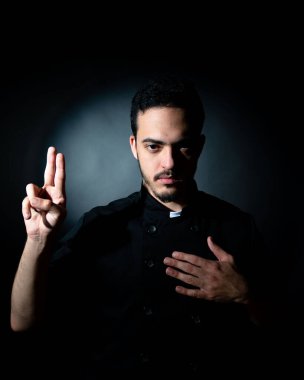 Şefin kıyafetleriyle siyah giyinmiş genç adam seyyar satıcı papaza benziyor. Ruhani bir kavram. yemek konsepti.