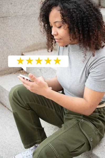 Kıvırcık saçlı kız, akıllı telefonuyla bir deneyim yaşarken gülümsüyor. İş konsepti.