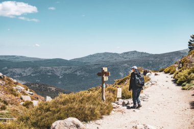 Sırt çantası ve okuma talimatlarıyla dağda bir gezgin. Yatay fotoğraf.