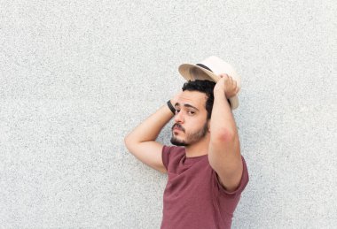 Genç adam kameraya bakarken şapkasını takıyor..