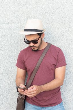 Cep telefonunu kullanan güneş gözlüklü genç bir adam.