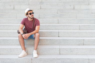 Gözlüklü genç adam merdivenlerde oturmuş fotokopi odasına bakıyor..