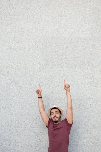 Bir fotokopi alanını işaret ederken şapka takan genç adam..