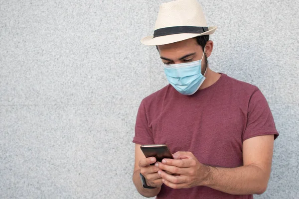 Akıllı telefonunu kullanan maskeli genç bir turist..