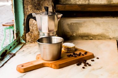 Kahve çekirdekli İtalyan sade kahvesi ve şekerli el yapımı kurabiye ve arkasında da Moka demliği. Pencereye yakın, klasik kahverengi arka plandaki her şey. Sağlıklı Kahvaltı.