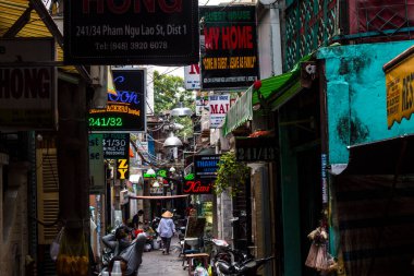 Ho Chi Minh City, Vietnam: 02 / 06 / 2020: sayısız otel, bar ve dükkan tabelasıyla dolu ana caddenin renkli perspektifi, insan ve motosikletle dolu