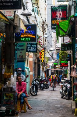 Ho Chi Minh City, Vietnam: 02 / 06 / 2020: sayısız otel, bar ve dükkan tabelasıyla dolu ana caddenin renkli perspektifi, insan ve motosikletle dolu