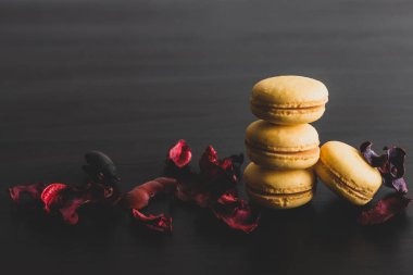 Sarı badem kurabiyeli limonlu kahvaltı sabahı yakın plan. Siyah arka planda Fransız tatlısına yakın plan ve çiçekler basit bir klasik kompozisyonda. Yemek fotoğrafçılığı.