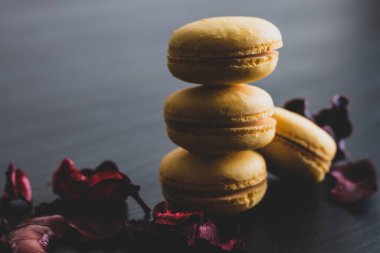 Sarı badem kurabiyeli limonlu kahvaltı sabahı yakın plan. Siyah arka planda Fransız tatlısına yakın plan ve çiçekler basit bir klasik kompozisyonda. Yemek fotoğrafçılığı.