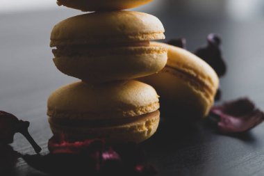 Sarı badem kurabiyeli limonlu kahvaltı sabahı yakın plan. Siyah arka planda Fransız tatlısına yakın plan ve çiçekler basit bir klasik kompozisyonda. Yemek fotoğrafçılığı.