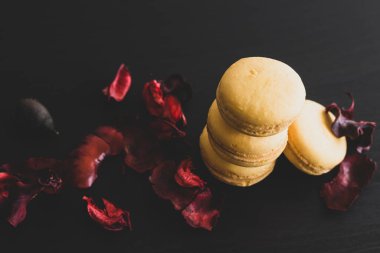 Sarı badem kurabiyeli limonlu kahvaltı sabahı yakın plan. Siyah arka planda Fransız tatlısına yakın plan ve çiçekler basit bir klasik kompozisyonda. Yemek fotoğrafçılığı.