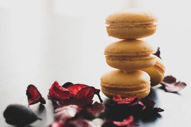 Sarı badem kurabiyeli limonlu kahvaltı sabahı yakın plan. Siyah arka planda Fransız tatlısına yakın plan ve çiçekler basit bir klasik kompozisyonda. Yemek fotoğrafçılığı.