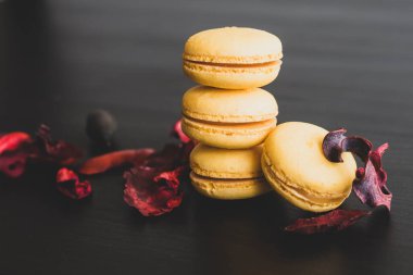 Sarı badem kurabiyeli limonlu kahvaltı sabahı yakın plan. Siyah arka planda Fransız tatlısına yakın plan ve çiçekler basit bir klasik kompozisyonda. Yemek fotoğrafçılığı.