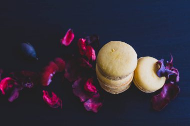 Sarı badem kurabiyeli limonlu kahvaltı sabahı yakın plan. Siyah arka planda Fransız tatlısına yakın plan ve çiçekler basit bir klasik kompozisyonda. Yemek fotoğrafçılığı.