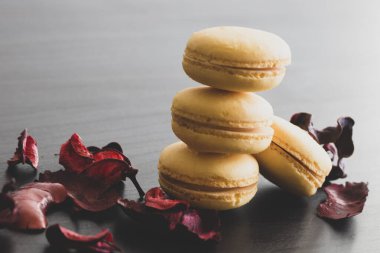 Sarı badem kurabiyeli limonlu kahvaltı sabahı yakın plan. Siyah arka planda Fransız tatlısına yakın plan ve çiçekler basit bir klasik kompozisyonda. Yemek fotoğrafçılığı.