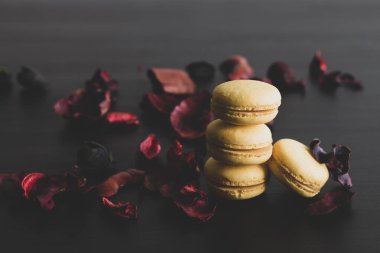 Sarı badem kurabiyeli limonlu kahvaltı sabahı yakın plan. Siyah arka planda Fransız tatlısına yakın plan ve çiçekler basit bir klasik kompozisyonda. Yemek fotoğrafçılığı.