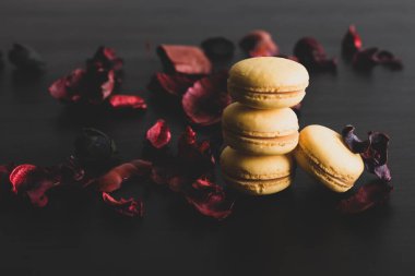 Sarı badem kurabiyeli limonlu kahvaltı sabahı yakın plan. Siyah arka planda Fransız tatlısına yakın plan ve çiçekler basit bir klasik kompozisyonda. Yemek fotoğrafçılığı.