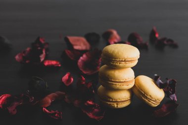 Sarı badem kurabiyeli limonlu kahvaltı sabahı yakın plan. Siyah arka planda Fransız tatlısına yakın plan ve çiçekler basit bir klasik kompozisyonda. Yemek fotoğrafçılığı.