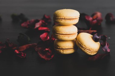 Sarı badem kurabiyeli limonlu kahvaltı sabahı yakın plan. Siyah arka planda Fransız tatlısına yakın plan ve çiçekler basit bir klasik kompozisyonda. Yemek fotoğrafçılığı.