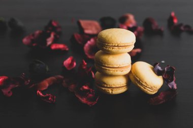 Sarı badem kurabiyeli limonlu kahvaltı sabahı yakın plan. Siyah arka planda Fransız tatlısına yakın plan ve çiçekler basit bir klasik kompozisyonda. Yemek fotoğrafçılığı.