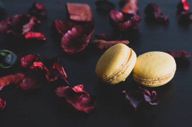 Sarı badem kurabiyeli limonlu kahvaltı sabahı yakın plan. Siyah arka planda Fransız tatlısına yakın plan ve çiçekler basit bir klasik kompozisyonda. Yemek fotoğrafçılığı.