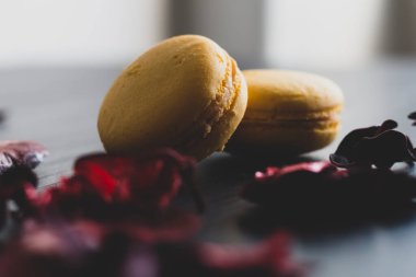 Sarı badem kurabiyeli limonlu kahvaltı sabahı yakın plan. Siyah arka planda Fransız tatlısına yakın plan ve çiçekler basit bir klasik kompozisyonda. Yemek fotoğrafçılığı.