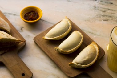 Geleneksel pişmiş Arjantin böreği lezzetli hamur işleri et ve ahşap arka planda lezzetli ekmekle doldurulmuş sandviç. Sağlıklı yemek.