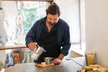 Erkek Barista süslü bir kahve dükkanında müşteriler için kahve makinesinde taze espresso hazırlıyor. Kahve dükkanında müşteriye servis yapan bir kafe sahibi..