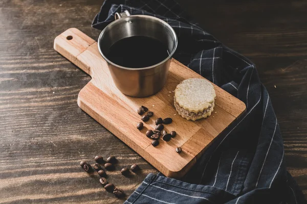 Italian american black coffee in a vintage cup with coffee beans around and a handmade cookie with sugar and a moka pot behind. Everything in vintage wood background and it is a Healthy and tasty Breakfast.