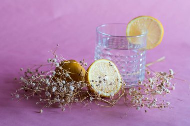Alkol içeceği (cin ve tonik kokteyl) limon meyvesi ve pembe arka planda izole edilmiş çiçek ile süslenmiştir. Limonlu ve otlu buzlu kokteyl..