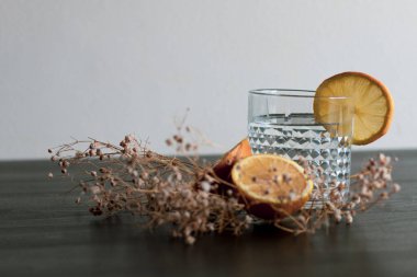 Alkol içeceği (cin ve tonik kokteyl) limon meyvesi ile süslenmiş ve kırsal arka planda güneş ışığıyla izole edilmiş çiçek. Limonlu ve otlu buzlu kokteyl..