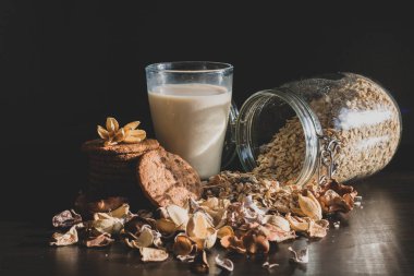 Sağlıklı sabah kahvaltısı, mısır gevreği, kepekli tahıl müsli, bardakta taze süt ve klasik koyu arkaplanda ev yapımı çikolatalı kurabiye. Estetik bileşim.