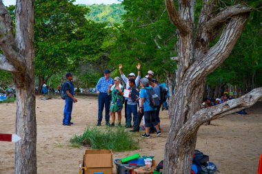 Komodo Dragon, the largest lizard in the world walks on ground. It is a dangerous prehistoric animal. Some tourists around and the rangers make the place safe. Komodo Island, Indonesia, south Asia.