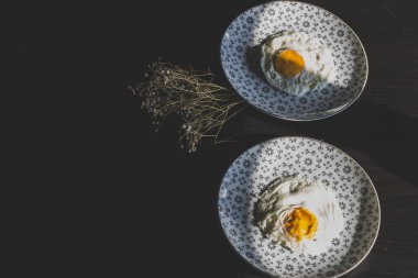 Homemade meal, Organic tasty cooked eggs for healthy breakfast on wood dark background and flowers in a vintage artistic composition. Simple food composition.