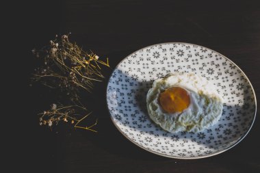 Homemade meal, Organic tasty cooked eggs for healthy breakfast on wood dark background and flowers in a vintage artistic composition. Simple food composition.