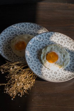 Homemade meal, Organic tasty cooked eggs for healthy breakfast on wood dark background and flowers in a vintage artistic composition. Simple food composition.