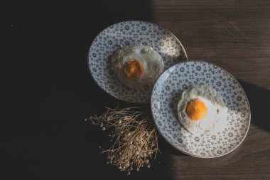 Homemade meal, Organic tasty cooked eggs for healthy breakfast on wood dark background and flowers in a vintage artistic composition. Simple food composition.