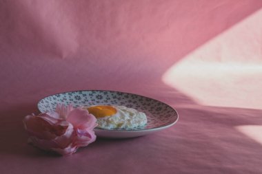Homemade meal, Organic tasty cooked eggs for healthy breakfast on pink background, fancy ceramic plates, and flowers in a vintage artistic composition. Simple food composition.