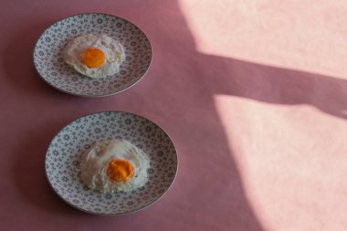 Homemade meal, Organic tasty cooked eggs for healthy breakfast on pink background, fancy ceramic plates, and flowers in a vintage artistic composition. Simple food composition.