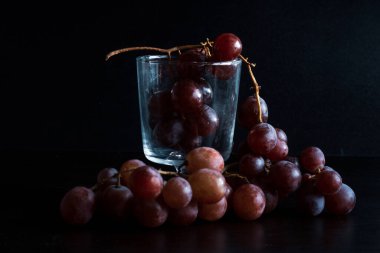 Red grapes, large bunch of fruits, fresh and tasty simple food on a dark background in a fancy minimal composition